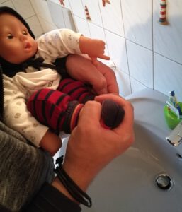 Kleines Baby wird über dem Waschbecken abgehalten
